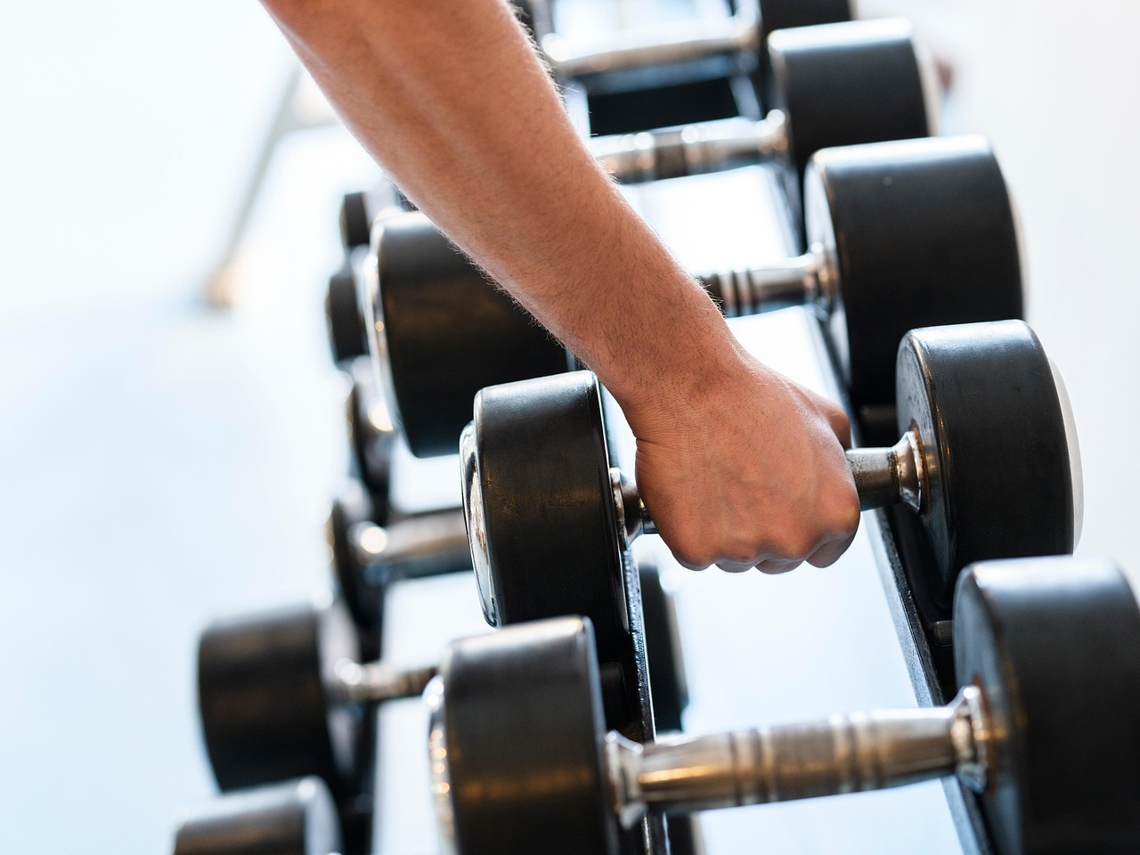 Close-up of a hand gripping a dumbbell during a strength exercise, illustrating grip strength as a simple, low-cost predictor of longevity