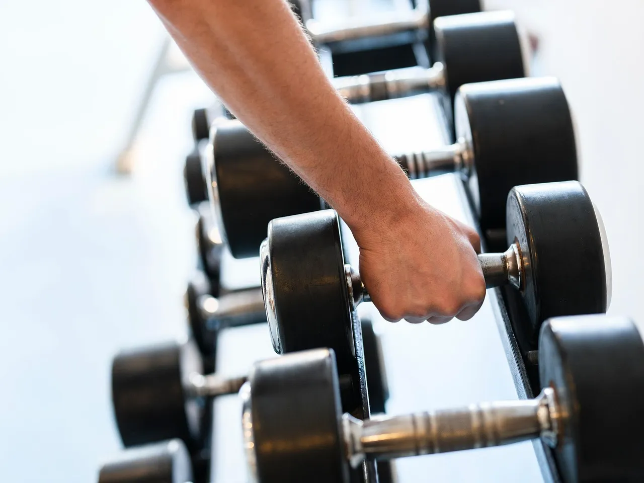 Close-up of a hand gripping a dumbbell during a strength exercise, illustrating grip strength as a simple, low-cost predictor of longevity