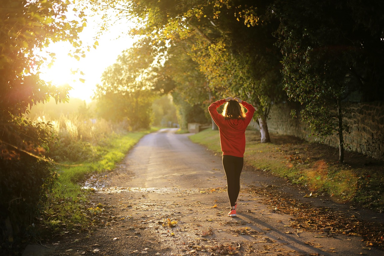 A woman walking briskly outdoors on a tree-lined path, an example of the aerobic exercise linked to healthier blood pressure