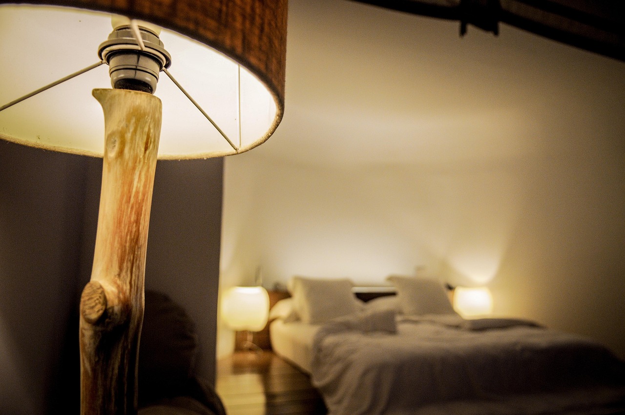 Dim bedroom at night lit by a single warm bedside lamp