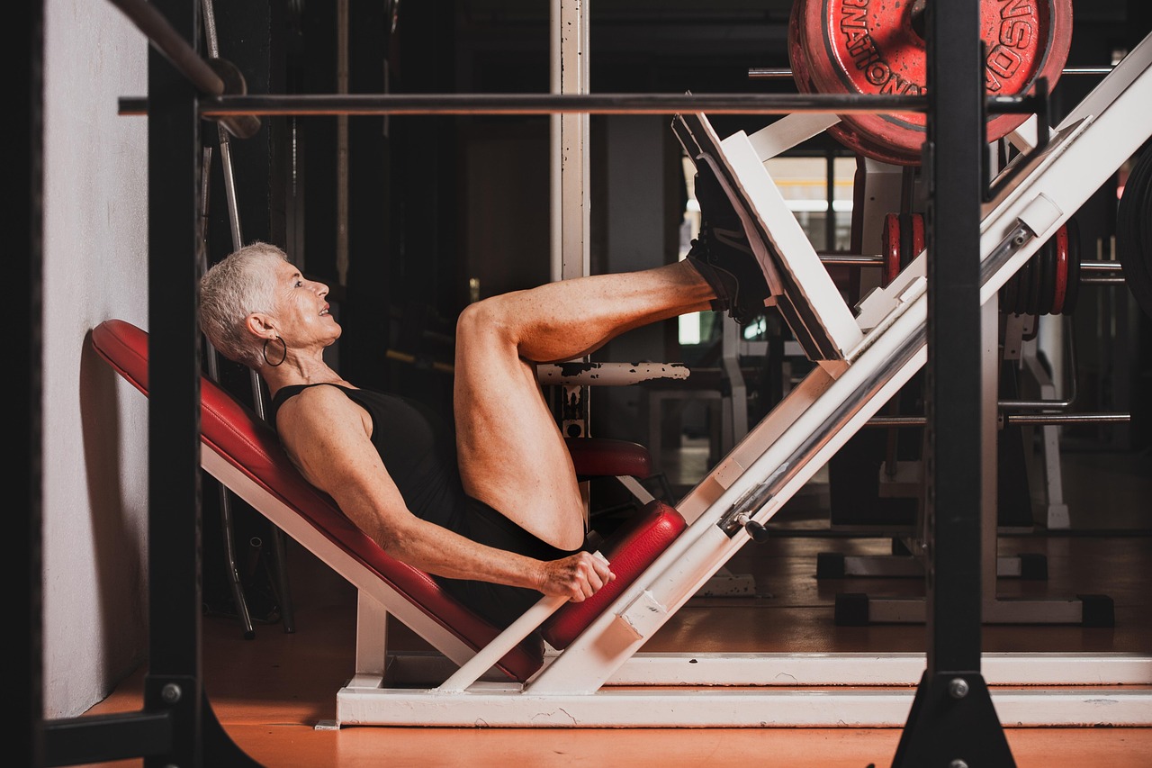 A senior woman performing a strength exercise on gym equipment, illustrating resistance training for muscle preservation
