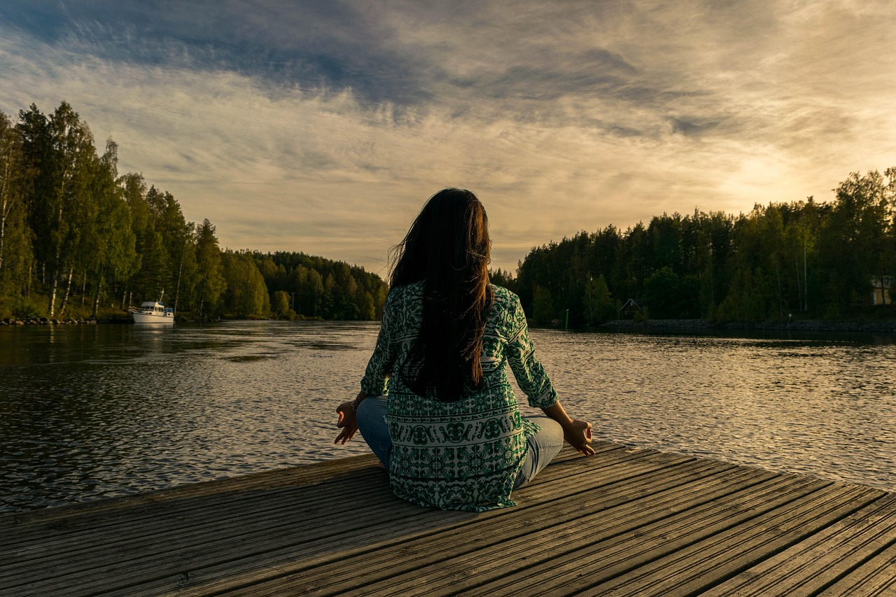 An older adult practices yoga outdoors by a lake at dusk, representing the physical activity that remains a foundation of cardiometabolic risk reduction