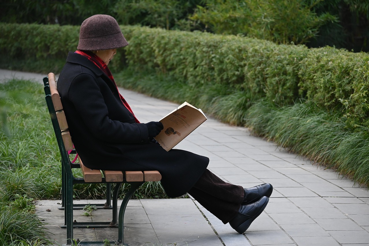 An older man reading a book on a park bench, an example of lifelong learning and mentally engaging leisure