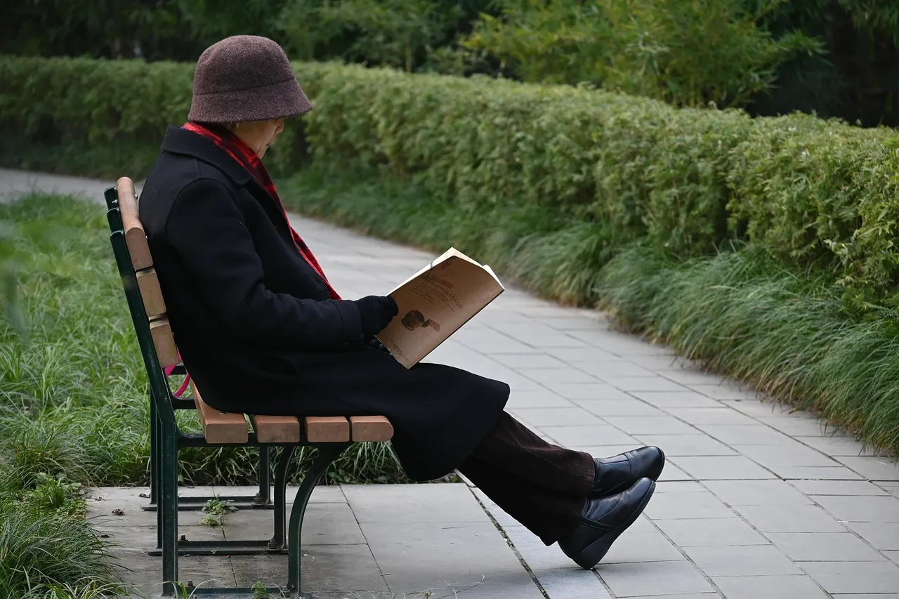 An older man reading a book on a park bench, an example of lifelong learning and mentally engaging leisure