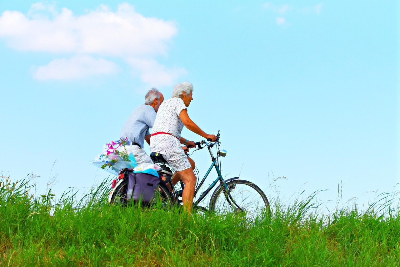 An older couple cycling together outdoors, illustrating the combined physical activity and social engagement linked to healthier brain aging
