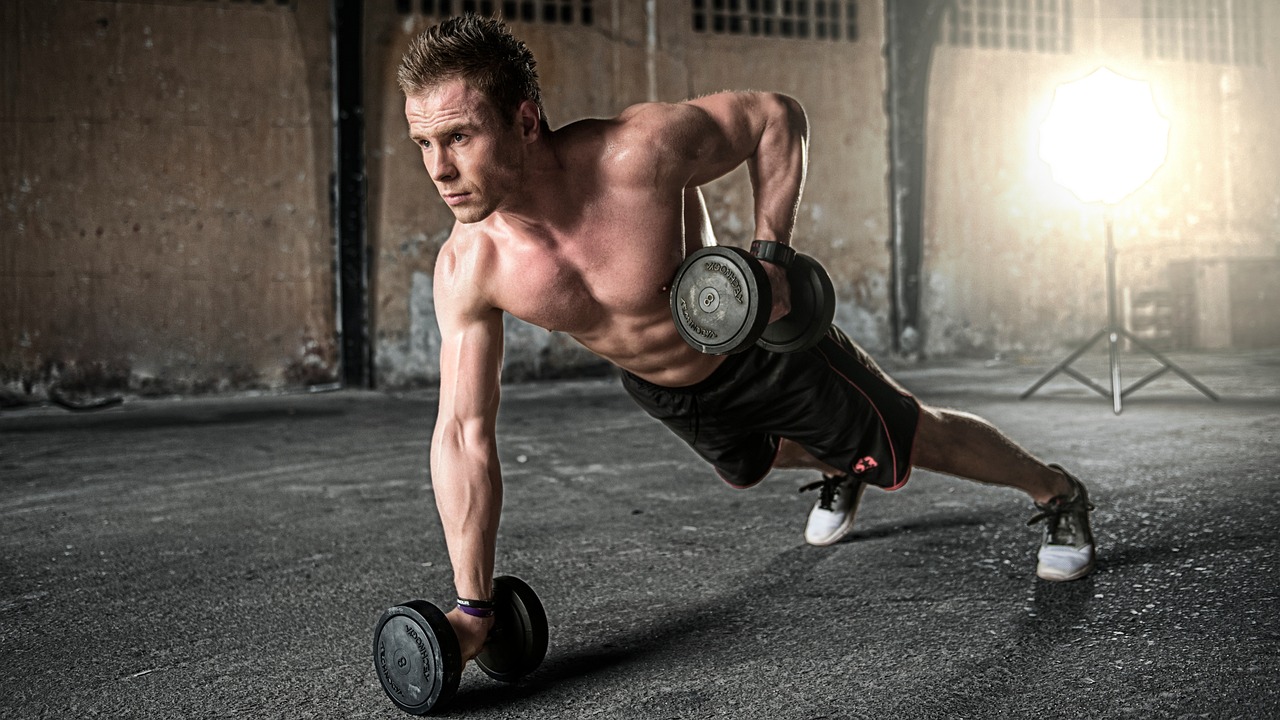 A man performing a strength-training exercise with dumbbells in a gym