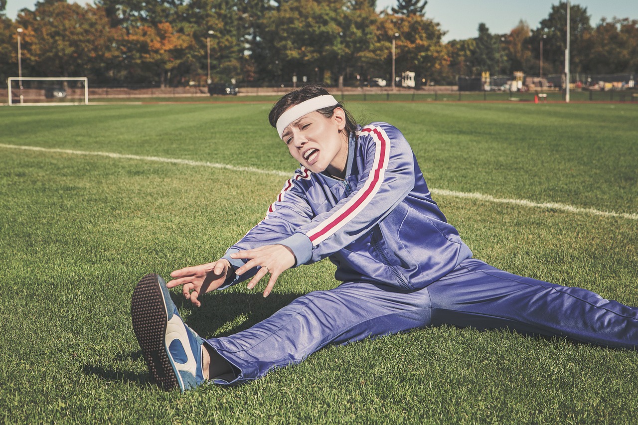A woman stretching on an outdoor athletic field, illustrating the joint, tendon, and connective-tissue function studied in collagen peptide research