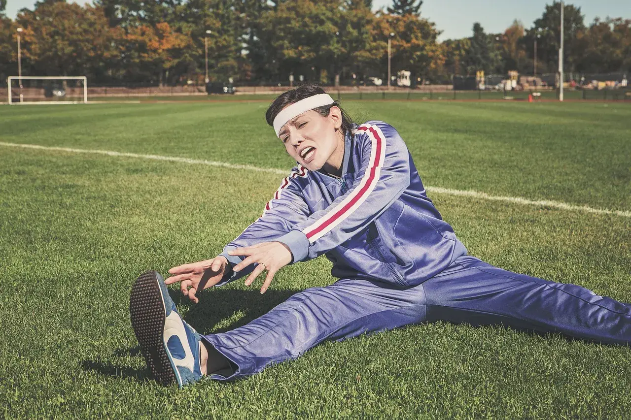 A woman stretching on an outdoor athletic field, illustrating the joint, tendon, and connective-tissue function studied in collagen peptide research