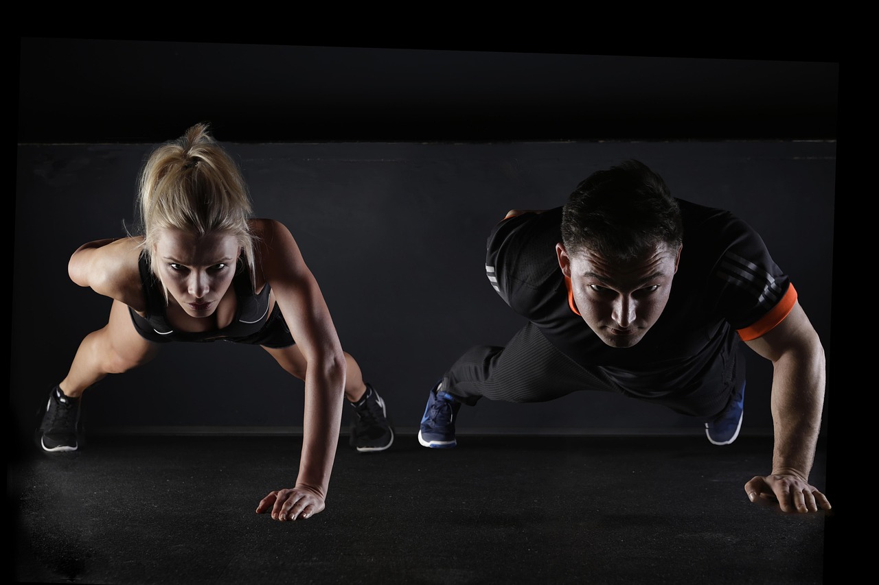 Two people doing push-ups together outdoors, demonstrating the kind of unfamiliar strength training that triggers delayed onset muscle soreness